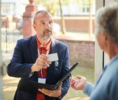 Salesman at door handing over business card