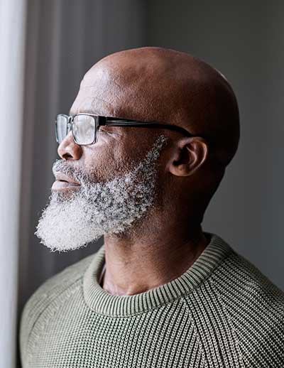 Man with beard looking out of window